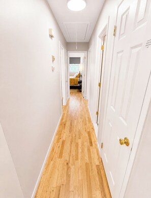 A hallway with wooden flooring, white walls, and doors with brass handles. - Spacious 4BR/2BT Hiking trails, Lake, Legoland & Warwick (Monroe)