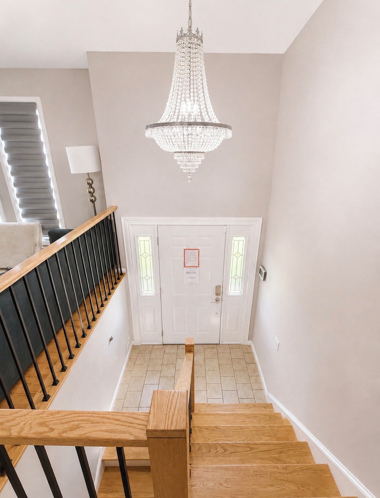Un escalier avec une rampe en bois, un lustre et une porte à panneaux de verre.