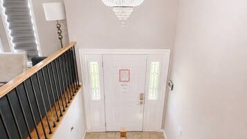 Un escalier avec une rampe en bois, un lustre et une porte à panneaux de verre.