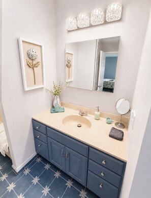 Un baño con lavabo, espejo y armarios.