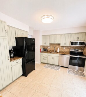 A modern kitchen with white cabinets, a black refrigerator, a microwave, an oven, and a coffee maker. - Spacious 4BR/2BT Hiking trails, Lake, Legoland & Warwick (Monroe)