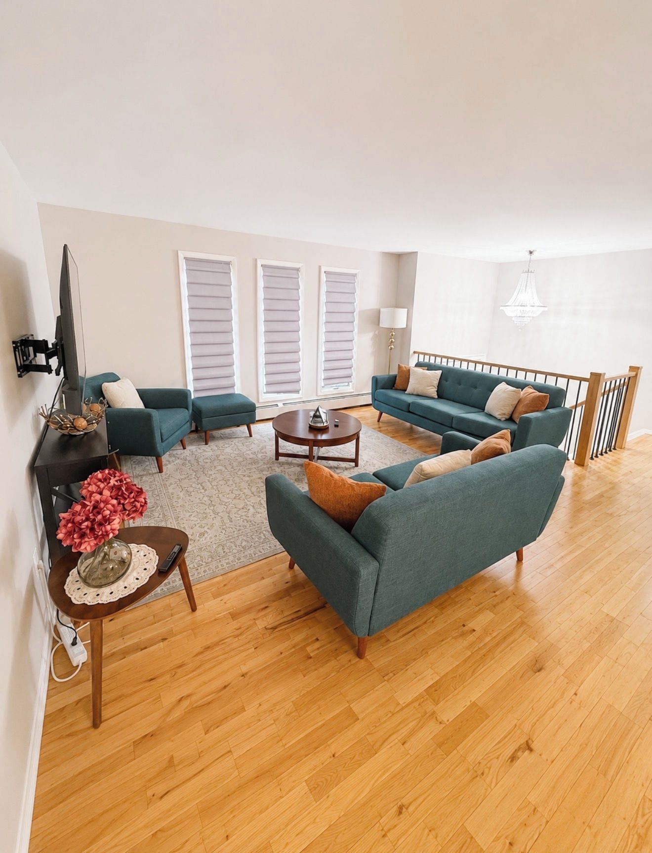 A spacious living room with a sofa set, a coffee table, and a TV mounted on the wall.