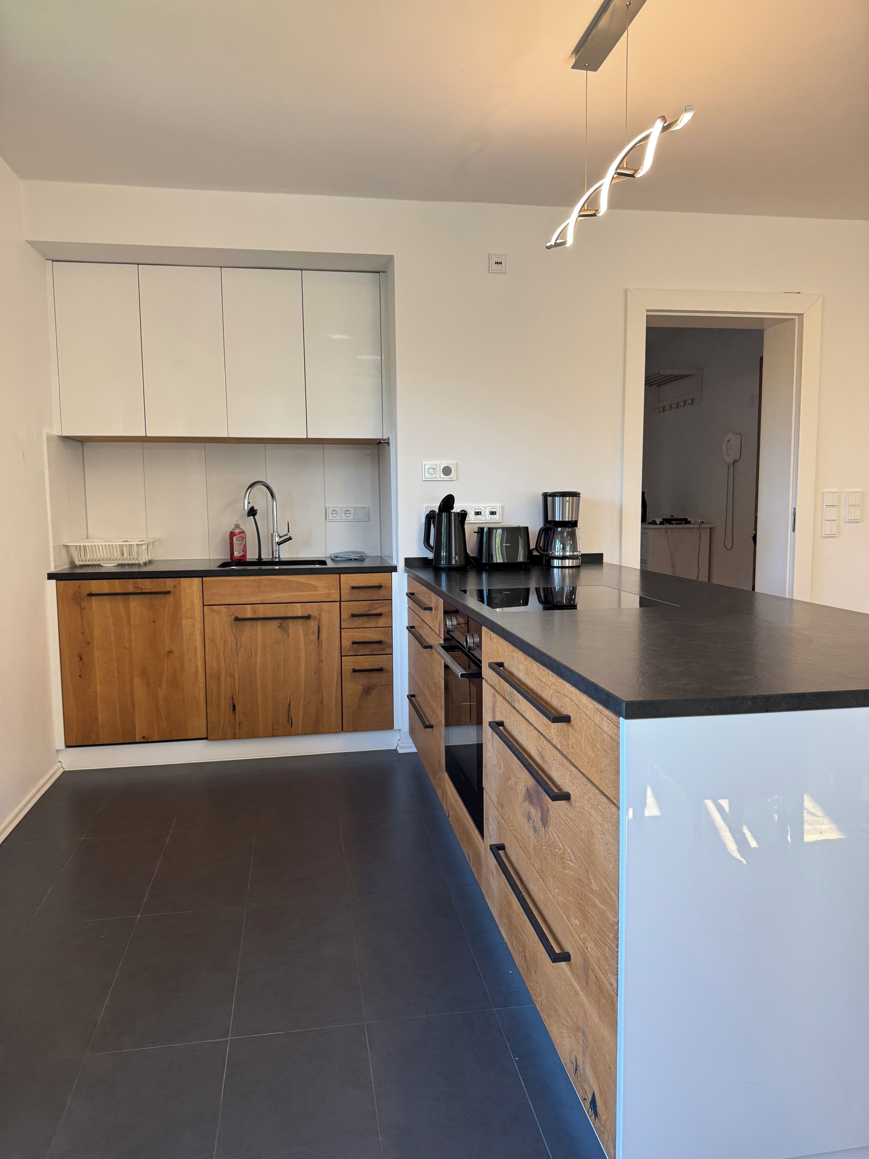 A modern kitchen with wooden cabinets, a black countertop, and stainless steel appliances.