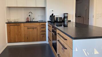 A modern kitchen with wooden cabinets, a black countertop, and stainless steel appliances.