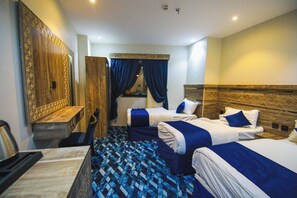 Ein Hotelzimmer mit zwei Betten, einem Schreibtisch, einem Stuhl, einem Spiegel und einem gestreiften Boden.