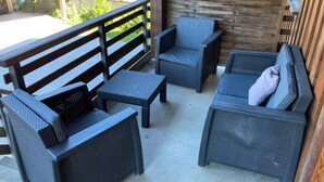 A patio area with wicker furniture, including a sofa and chairs, and a wooden fence in the background. - Apartment near the lake with a terrace offering mountain views. (Doussard)