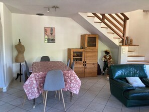 Ein Essbereich mit Tisch, Stühlen, einer Puppenmannequin, einem Schrank und einer Treppe.