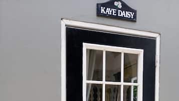 En sort dør med et hvidt vinduesramme og et skilt over, der står 'KAYE DAISY'.