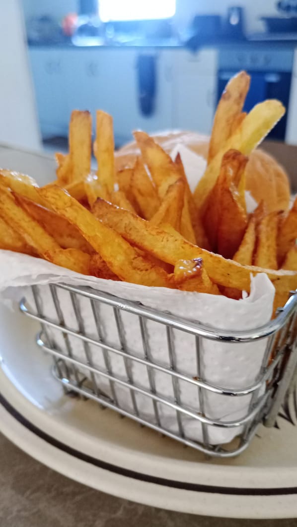 A basket of golden-brown fries on a white plate.