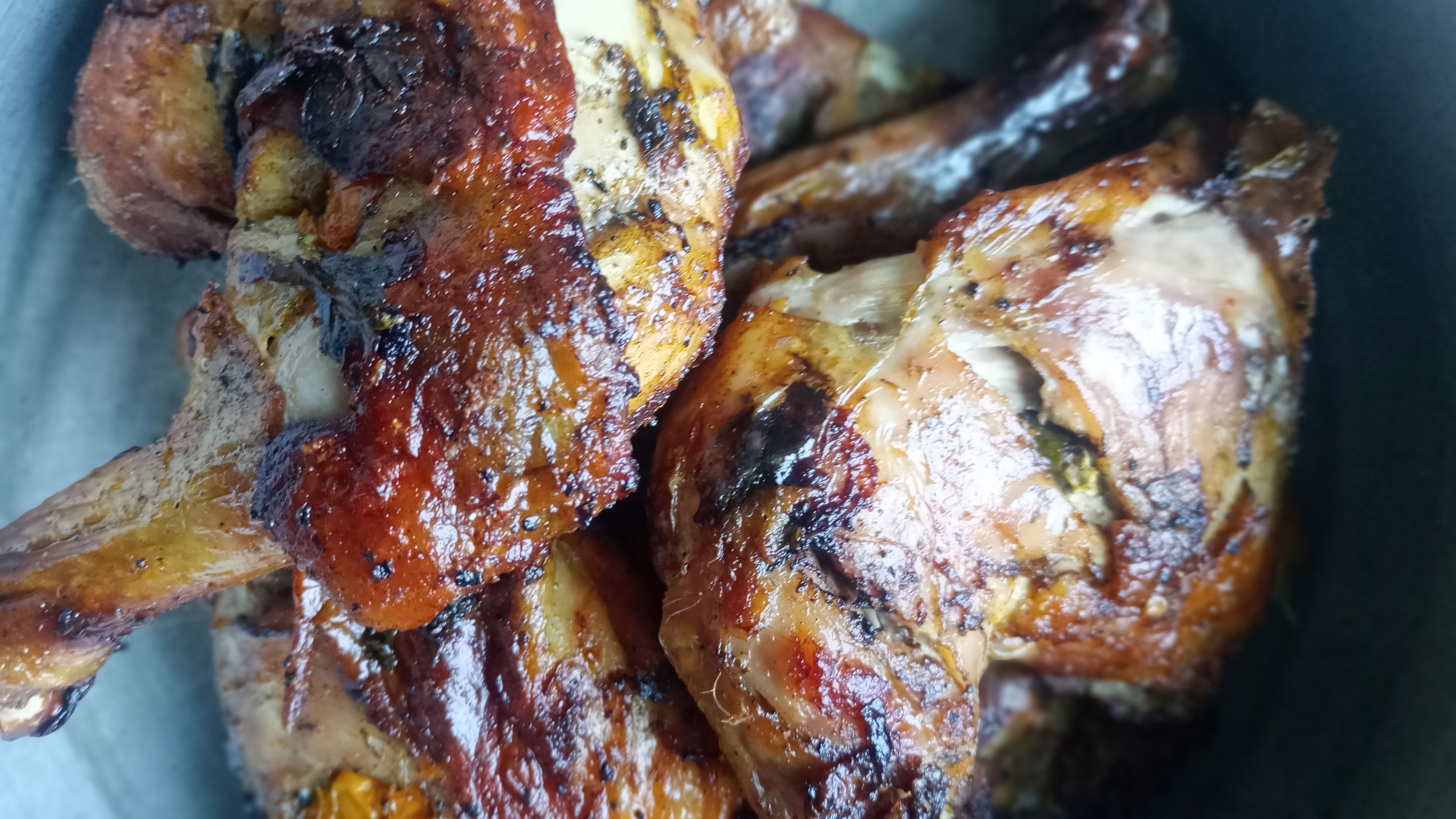 A close-up of roasted chicken with a glossy, caramelized exterior.