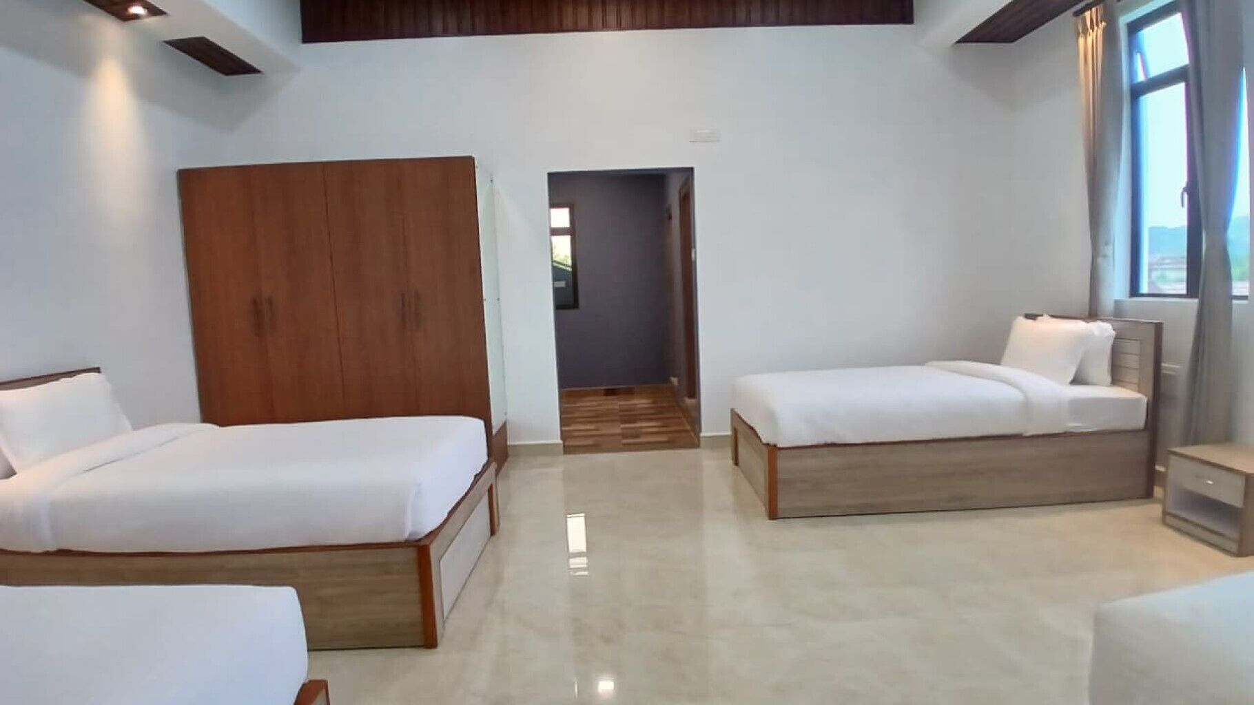 Habitación de hotel con dos camas, un armario y vistas al exterior.