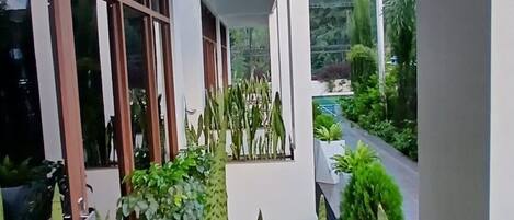 A covered outdoor area with a view of a road and greenery.