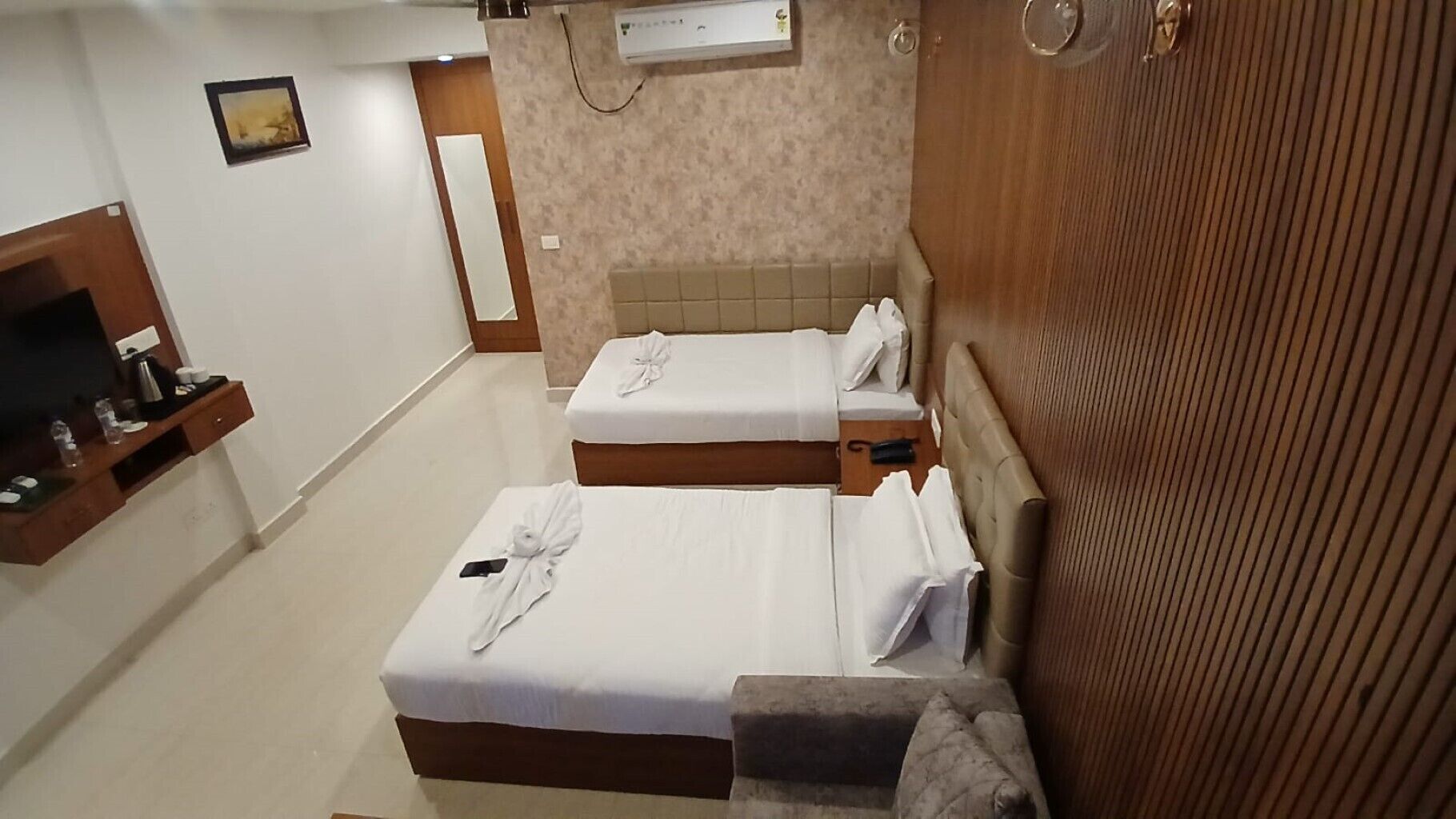 Habitación de hotel con dos camas, un televisor, un minibar y un armario de madera.