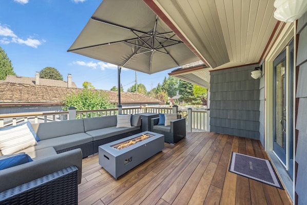 An outdoor deck with a fire pit, seating area, and a covered section.