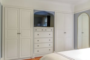 A bedroom with a bed, a wardrobe with multiple drawers, and a mirror.
