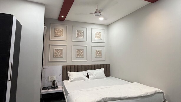 Un dormitorio con cama, mesita de noche, ventilador de techo y un cuadro colgado en la pared.