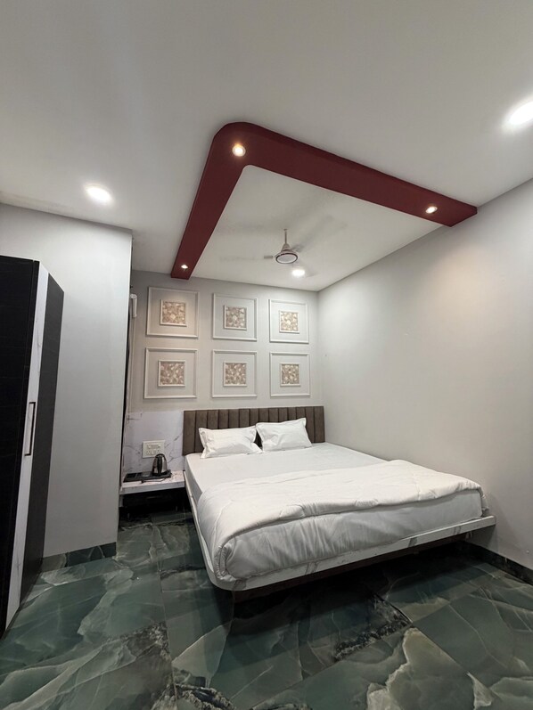 Un dormitorio con cama, mesita de noche, ventilador de techo y un cuadro colgado en la pared.