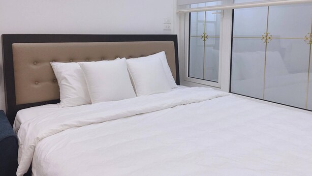 Una habitación de hotel con cama, cabecera y ventana con persianas.