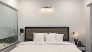 Habitación de hotel con cama, mesita de noche, teléfono en la pared y lámpara de pared.