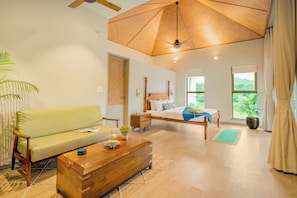 A spacious room with a bed, a sofa, a wooden chest, and a ceiling fan. - Staymaster Villa Zelora - 4BR with Pool  (Siolim)