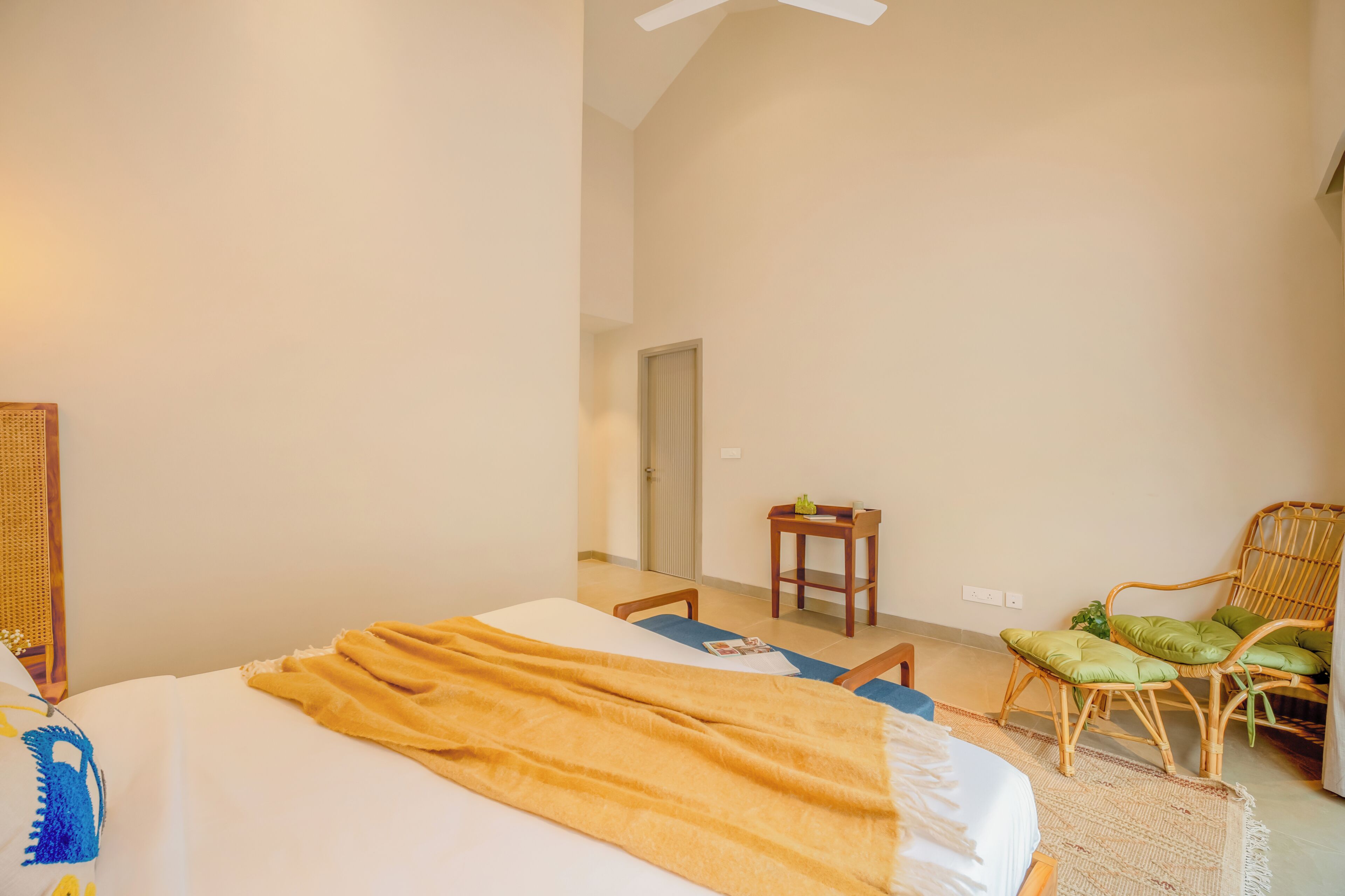 Une chambre à coucher avec un lit, une chaise, une petite table et une porte.