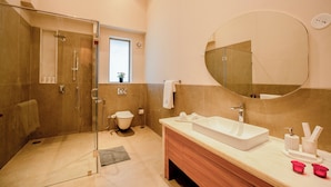 Een moderne badkamer met een inloopdouche, toilet, wastafel met kastje en een grote spiegel.