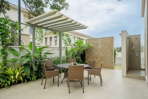 An outdoor patio with a round table and chairs, surrounded by various plants. - Staymaster Villa Zelora - 4BR with Pool  (Siolim)
