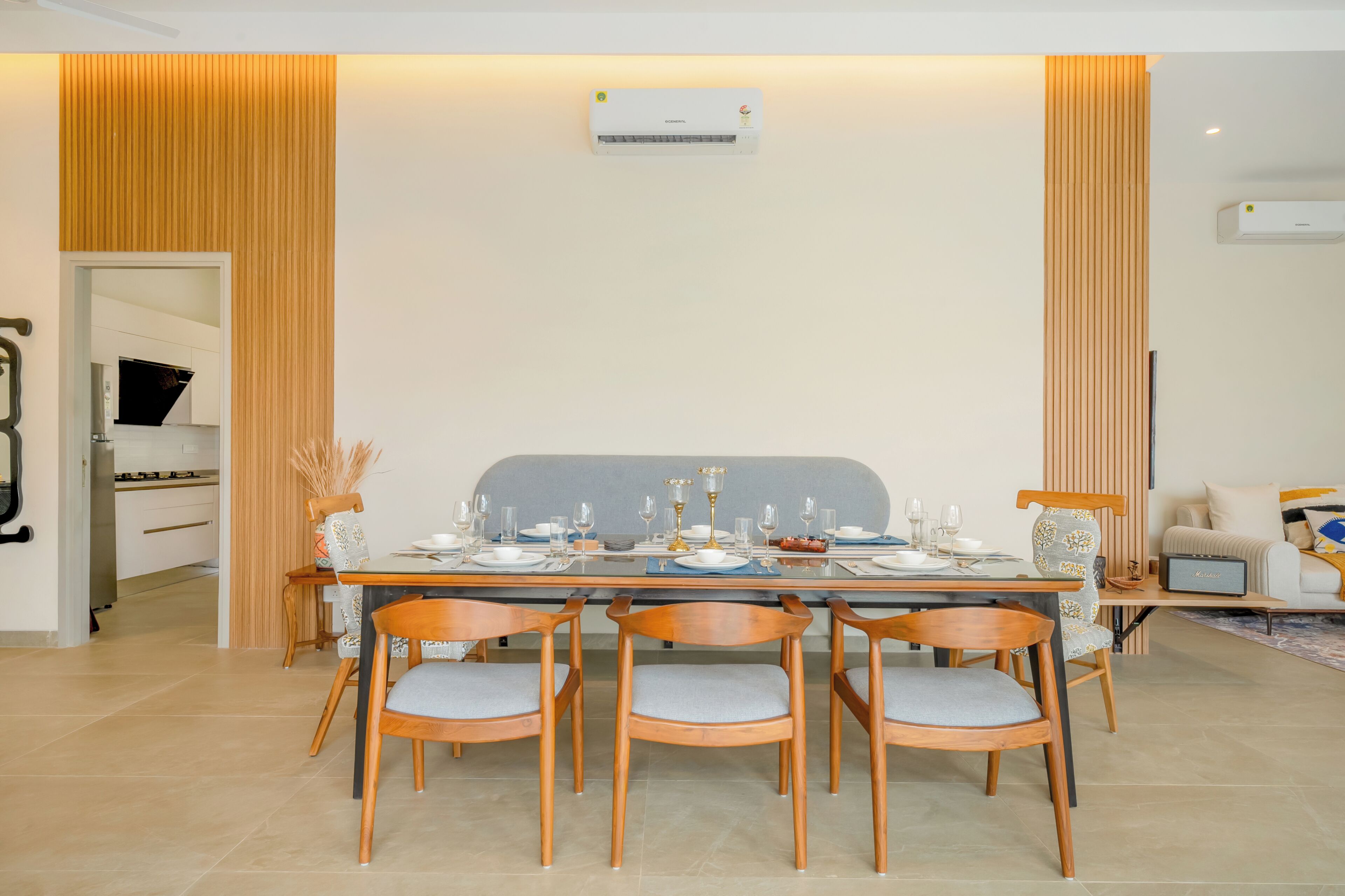 Un coin repas avec une table dressée pour quatre personnes, entourée de chaises en bois dotées de coussins gris.