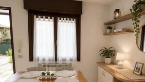 Una zona de menjador amb una taula de fusta, quatre cadires i una finestra amb cortines.