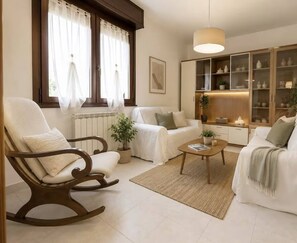 A living room with a sofa, a rocking chair, a coffee table, and a cabinet with glass doors. - Apartment in a 2-bedroom House (Grezzana)