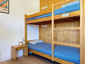 A bunk bed room with a wooden frame, a small bedside table, and a lamp. - Les Grandes Platières (Val Claret) by Interhome (Tignes)