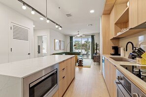 A modern kitchen with a central island, built-in appliances, and a view to the outside. - 4BDR South Lamar Stay w/ Pool, Rooftop, Restaurant | The Code by AvantStay (Austin)