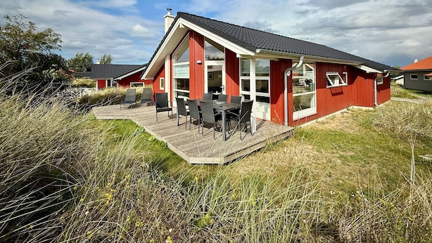 Ein rotes Haus mit einer Veranda und Sitzgelegenheiten im Freien.