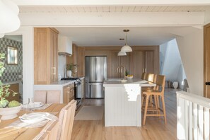 Cozinha moderna com armários de madeira, eletrodomésticos de aço inoxidável e uma ilha central com assentos.
