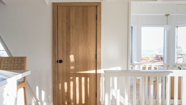 A room with a wooden door, white walls, and a white railing. - A-Frame Cabin w/ Hot Tub + Firepit | EV Charger + Steps to Trails | The A-List (Lake Arrowhead)