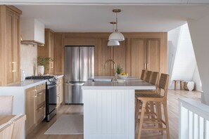 Uma cozinha moderna com armários de madeira, eletrodomésticos de aço inoxidável e uma ilha central com assentos.