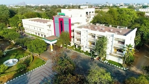 A hotel with multiple floors, a central entrance, and a surrounding garden.