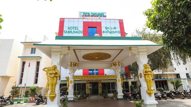 A hotel entrance with a signboard, a covered entrance area, and golden statues.