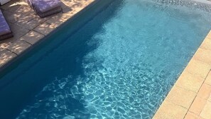 A clear swimming pool with a tiled edge and a lounge area with cushions. - Tropical Santai Retreat - Pool with separate flat (Toukley)