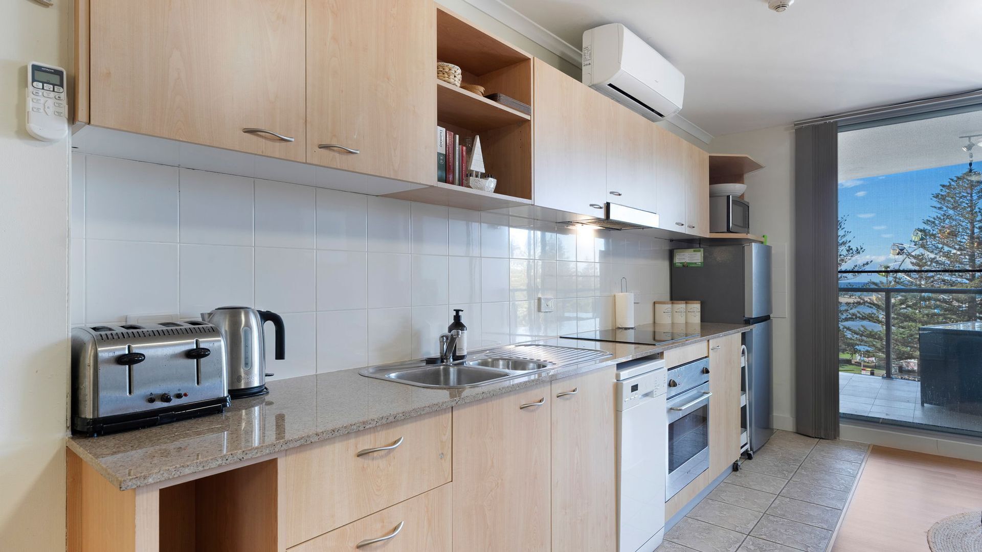 A modern kitchen with a built-in oven, a microwave, and a stainless steel sink.