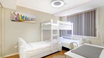 A room with bunk beds, a desk, and a window with blinds.
