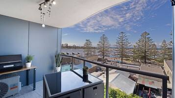 A balcony with a view of a body of water, trees, and buildings.