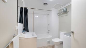 A bathroom with a bathtub, toilet, and a shower area.
