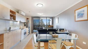 A modern kitchen with a dining area, a large window, and a view of trees.
