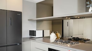 A modern kitchen with a stainless steel refrigerator, a microwave, a stove, and a coffee maker. - The Accessible Oasis - 3 bedroom disability apartment (The Entrance)