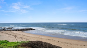 A beach with a rocky breakwater, sandy shore, and ocean waves. - The Accessible Oasis - 3 bedroom disability apartment (The Entrance)
