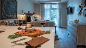 A well-lit room with a dining table set for a meal, a bed with a view, and a ceiling fan. - 4 Suites + Balconies | Steps to DT Square | Paso Park Suites Buyout (Paso Robles)