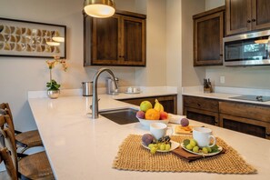 Een moderne keuken met houten kastjes, een roestvrijstalen spoelbak en een fruitschaal op het aanrecht.