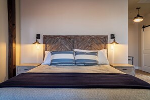 Ein Bett mit einem Holz-Kopfteil, zwei Nachttischlampen und gestreifte Kissen.
