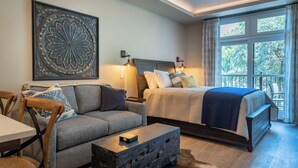 A modern bedroom with a large bed, a sofa, a coffee table, and a decorative wall piece. - 4 Suites + Balconies | Steps to DT Square | Paso Park Suites Buyout (Paso Robles)